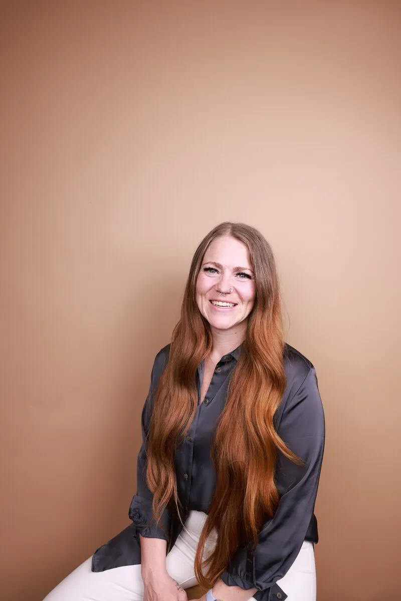 Mary J smiling, seated against a warm tan backdrop