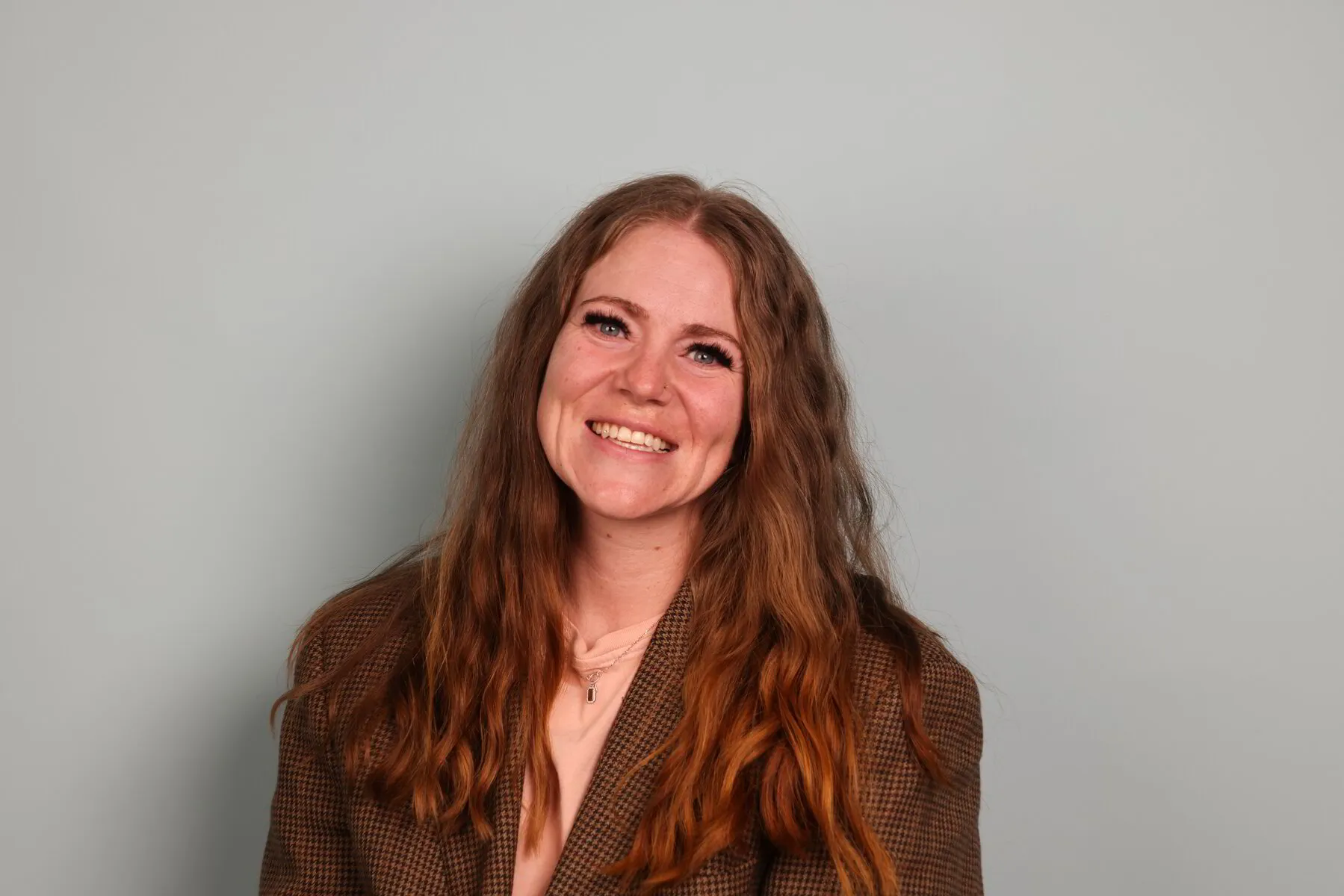 Mary J, smiling, with long auburn hair and a brown tweed blazer